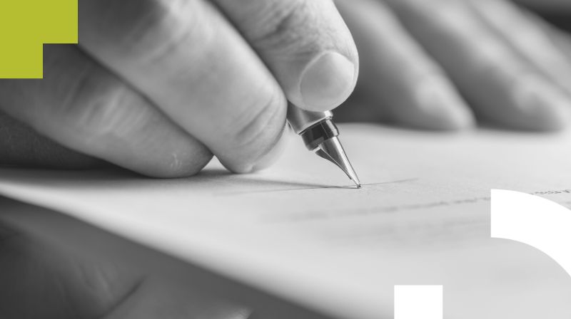 Foto detalle de una mano firmando con pluma en un papel