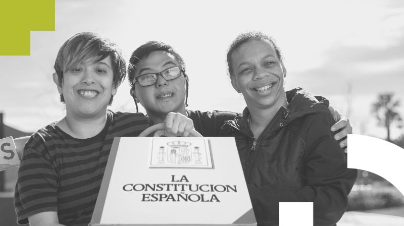 Tres personas con discapacidad sujetando la Constitucin Espaola